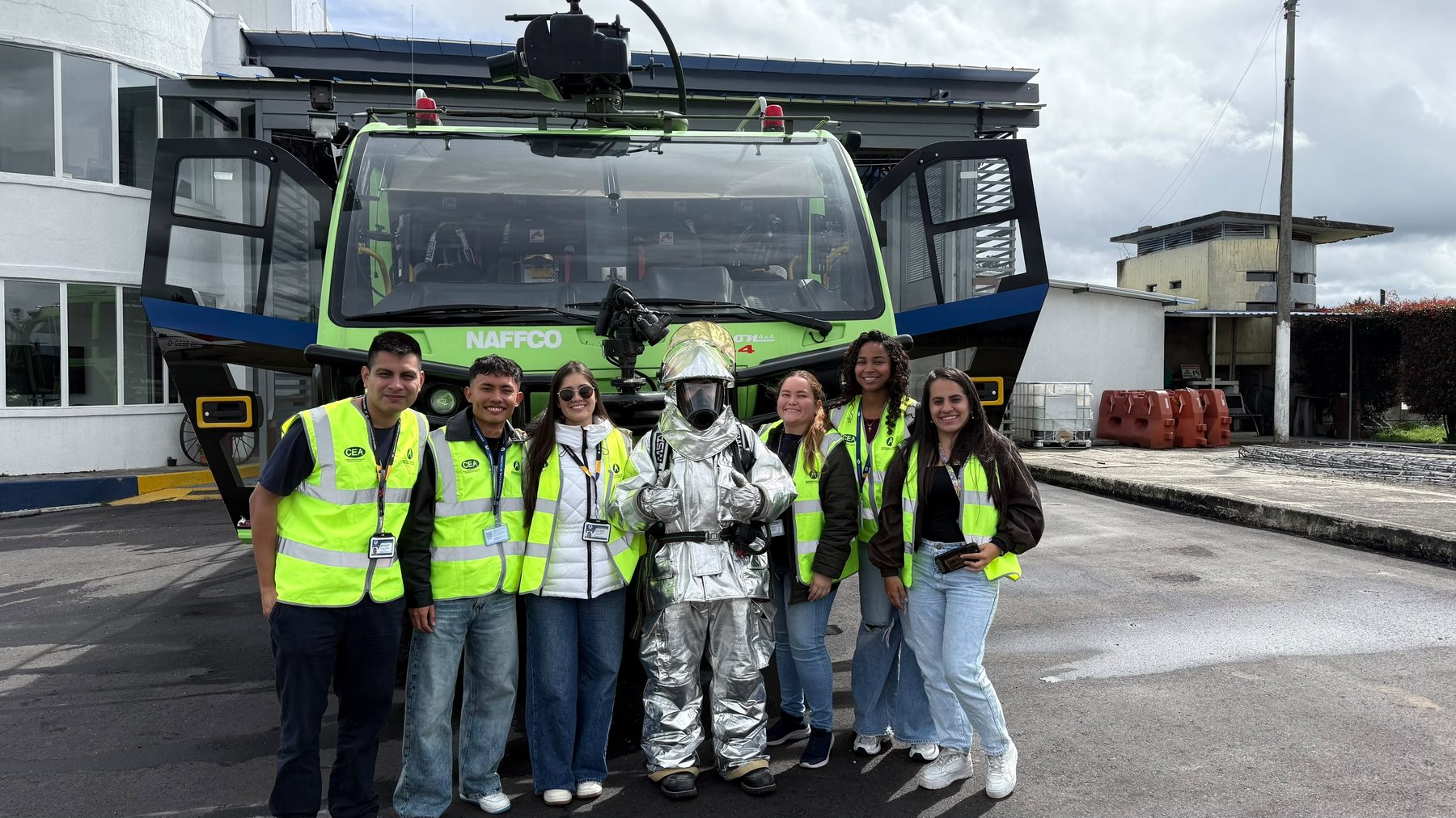 Equipo de operadores aeronáuticos en jornada de campo, junto a un vehículo de rescate y extinción de incendios y personal de bomberos aeroportuarios.
